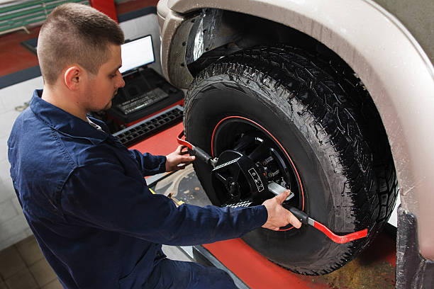 A guy balancing a tire from a white vehicle